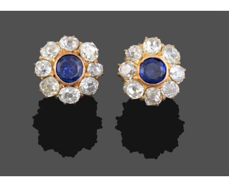 A Pair of Sapphire and Diamond Cluster Earrings, the round cut sapphire in a yellow rubbed over setting within a border of ol