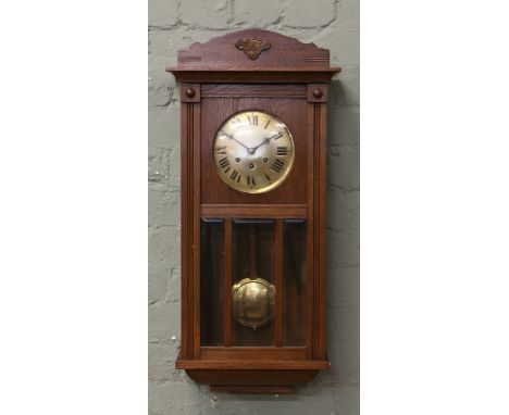 An oak cased eight day Westminster wall clock with circular brass dial having black enamel Roman numeral markers.