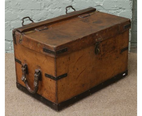An antique tan leather carriage trunk with metal mounts, strap loops and leather carrying handles.