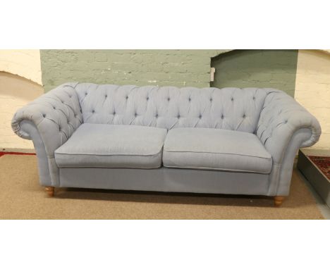 A Chesterfield style sofa upholstered in pale blue fabric.