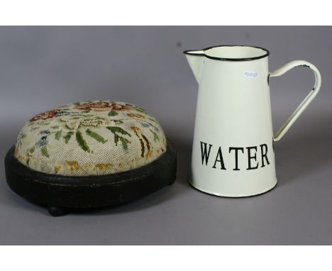 An enamel water jug and a Victorian footstool with woolwork upholstery.