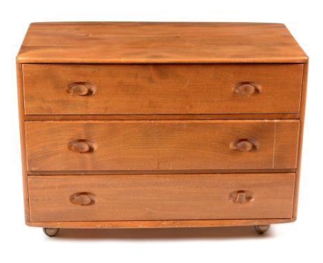 Ercol: an elm Windsor dressing chest , No 412, the shaped rectangular top above three drawers with oval protruding handles, r