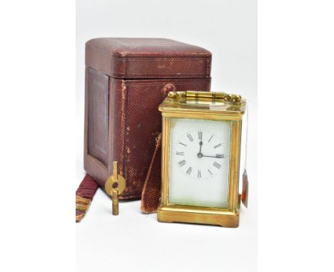 A BRASS CARRIAGE CLOCK WITH CASE, a white dial, roman numerals and blue hands, within a brass and four glass panel case, oval