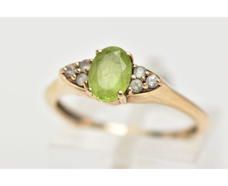 A 9CT GOLD PERIDOT RING, an oval cut peridot, accented with six circular cut cubic zirconia, in a yellow gold prong setting, 