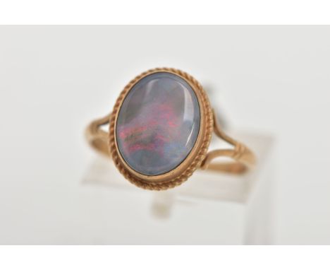 A 9CT GOLD OPAL RING, of an oval design, set with an opal cabochon, displaying blue and red play of colour, collet mounted wi