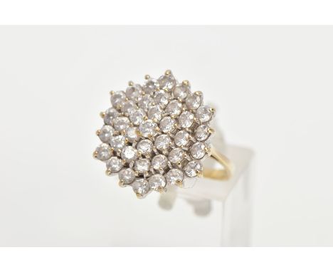 A 9CT GOLD CUBIC ZIRCONIA CLUSTER RING, thirty seven circular cut cubic zirconia within a yellow metal prong setting, leading