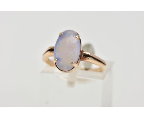 A YELLOW METAL OPAL RING, designed with a four claw set oval opal cabochon, bifurcated shoulders leading onto a plain polishe