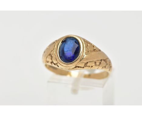 A 9CT GOLD SIGNET RING, of an oval design, set with an oval cut blue stone assessed as paste, textured design to the shoulder