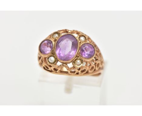 AN AMETHYST AND SEED PEARL DRESS RING, three stone ring set with a central oval cut amethyst flanked with circular amethysts 