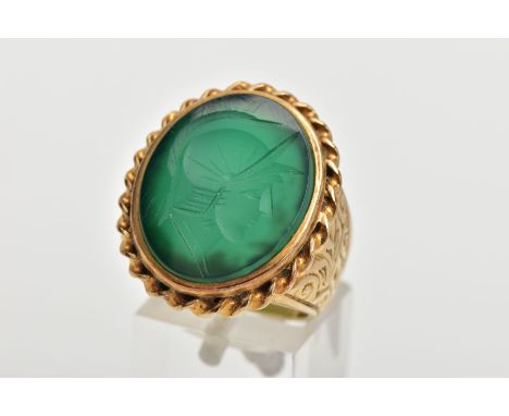 A GENTS 9CT GOLD INTAGLIO RING, of an oval form, engraved soldiers head within a green chalcedony, collet mounted within a ro