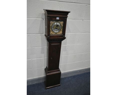 AN OAK GRANDDAUGHTER CLOCK, the square hood enclosing a brass and silvered dial, spandrels to each corner surrounding a 5 1/2
