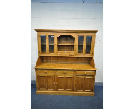 A LARGE PINE DRESSER, the top section with four glazed doors flanking and open shelf section and three drawers, over a base w