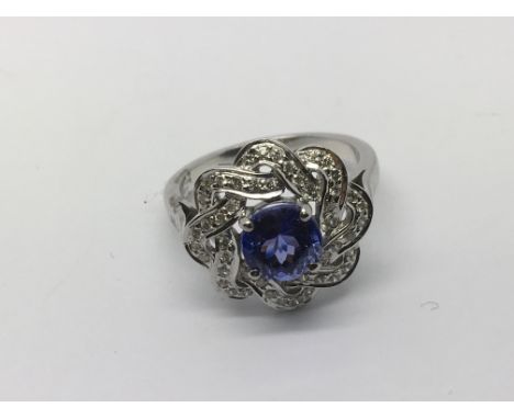 A white gold ring set with a central tanzanite surrounded by small diamonds, approx 5.2g and approx size O-P.