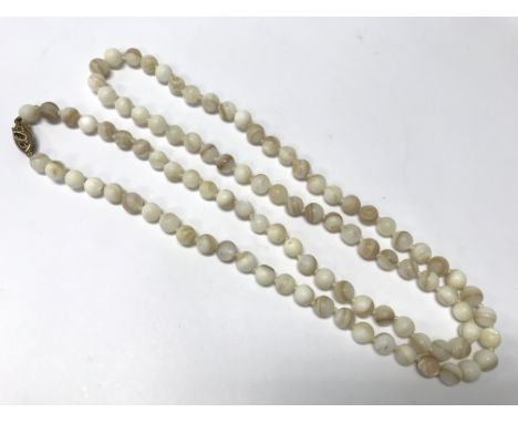 A string of white mother of pearl beads with a yellow gold 9ct gold clasp.