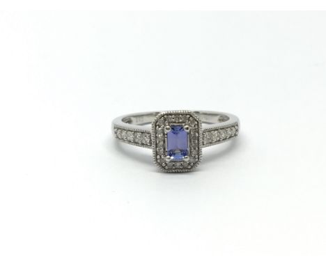 A white gold diamond and tanzinite cluster ring with diamond shoulders