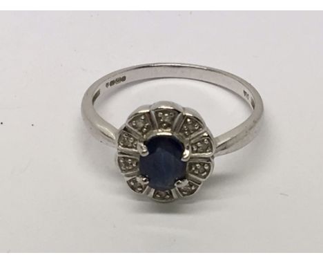 A 14 carat white gold ring set with a blue sapphire and small diamonds Ring Size R.