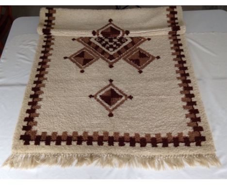 A hand made cream & brown wool rug, 115cm x 200cm.