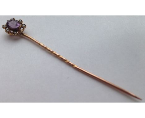 A Victorian gold stick pin set with a central oval amethyst surrounded by 6 seed pearls. Tests as 15ct gold