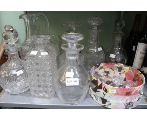 A shelf containing a wide selection of cut glass and other decanters with spare stoppers