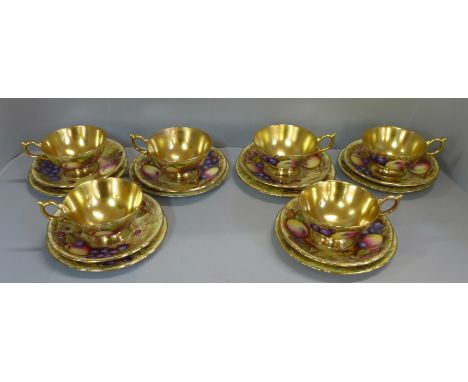 A set of six Aynsley cups, saucers and tea plates, decorated with fruit and berries in gold rim and cup, transfer printed, on