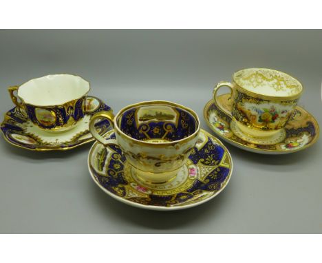 Three 18th/19th Century cups and saucers, two with painted panels of landscapes, one decorated with panels of fruit (cup rest