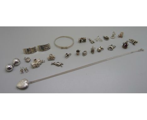 Eighteen silver and white metal charms, three pairs of silver earrings, a silver locket on chain, and a child's silver bangle