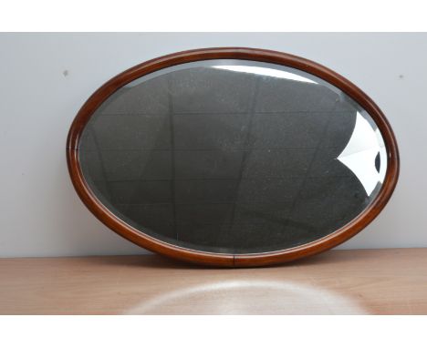 A mahogany framed oval wall mounted mirror, with a bevelled mirror plate, 50cm x 75cm 