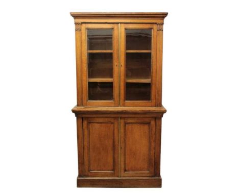 Late Regency light oak two height bookcase, the upper section enclosed by twin glazed doors, the projecting base enclosed by 