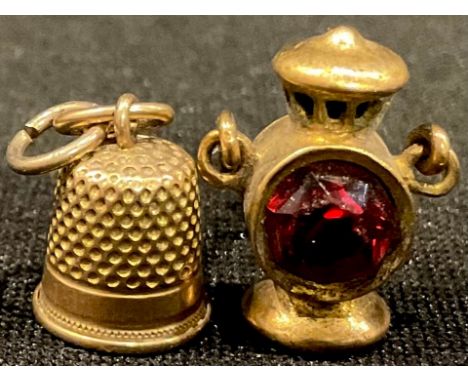 A miniature yellow metal railway signal lamp charm; a miniature thimble charm 