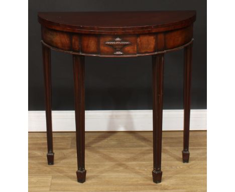 An Adam Revival mahogany demilune card table, folding top enclosing a baize lined playing surface, above a deep frieze carved