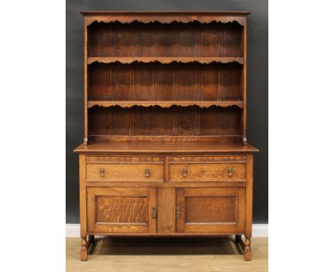 An oak dresser, moulded cornice above a pair of plate racks, the base with two short drawers above two panel doors, 192cm hig