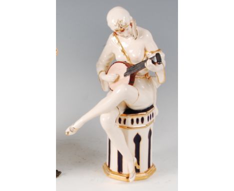 Royal Dux - an Art Deco glazed pottery figure of a semi-nude seated female playing a mandolin, heightened in gilt, with raise
