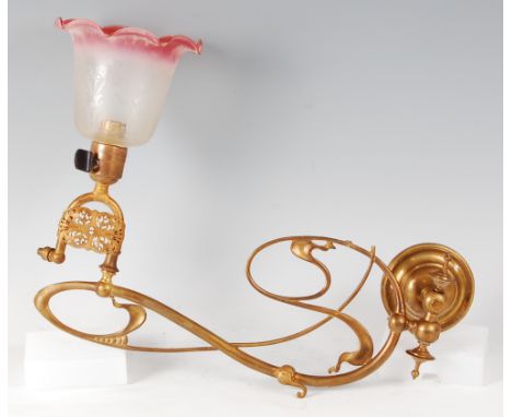 An Art Nouveau brass single wall light, of interlaced stylised form having swing action, with floral acid etched shade, lengt