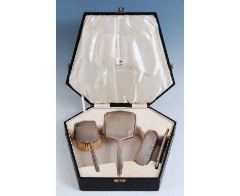 An Art Deco engine turned silver four-piece dressing table set, comprising hand mirror, two brushes, and a comb, each having 