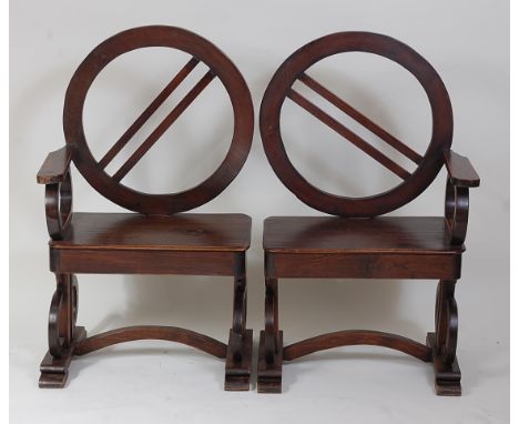 A pair of unusual 1920s possibly Austrian oak hall chairs, each having single opposing arm rest, circular slat backs and roun