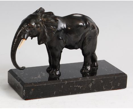 An Art Deco bronzed spelter figure of a standing elephant, trunk down (lacking one tusk), raised on polished and chamfered gr