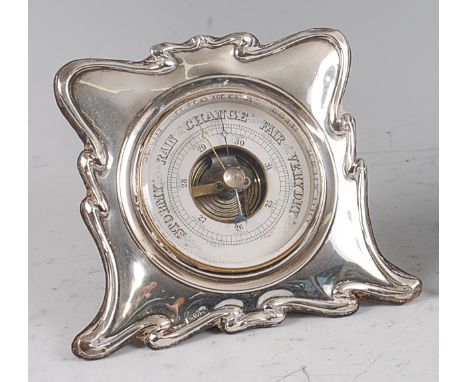 An Art Nouveau silver framed circular desk barometer, having a stylised and shaped outline to velvet clad easel back, maker R