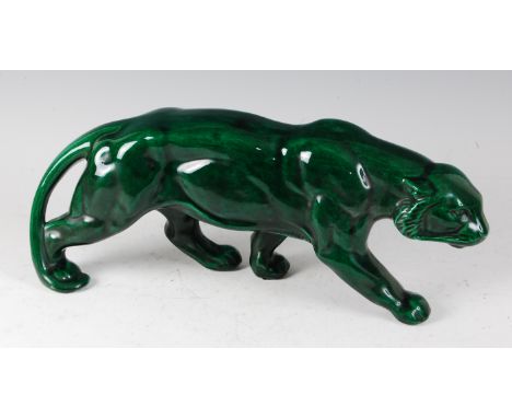 An Art Deco glazed ceramic model of a prowling lion stalking its prey, underglaze green painted, length 47cm. A few minor gla
