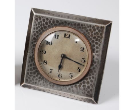 An early 20th century Tudric pewter bedside alarm clock, having a silvered circular dial with square hammered outer frame, st