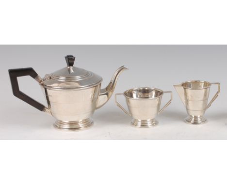 An Art Deco silver three-piece teaset, comprising teapot with hinged cover, angular ebonised handle and finial, a twin handle