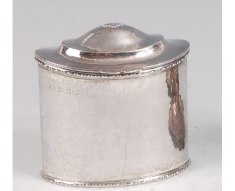 A late Arts &amp; Crafts hammered silver oval tea caddy, the domed hinged cover with thumb-moulded edge, with upper and lower
