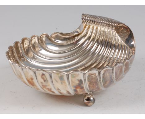 An early 20th century silver sweetmeat dish, in the form of a scallop shell, with rolled handle and raised on three ball feet