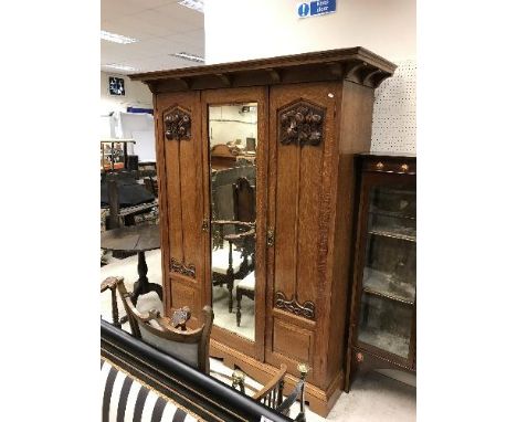 A late Victorian oak wardrobe in the Art Nouveau manner, the central mirrored door flanked by two further doors, each carved 