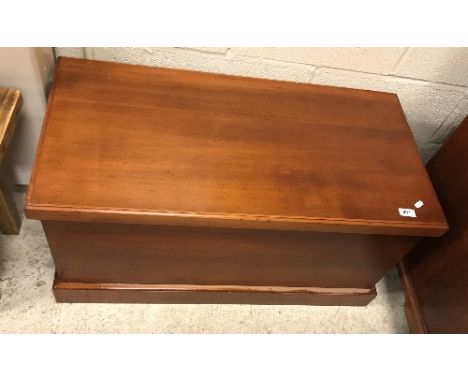 A stained cedar trunk, the plain top over plain sides with wrought iron handles, raiesd on a plinth base, 89 cm wide x 45 cm 