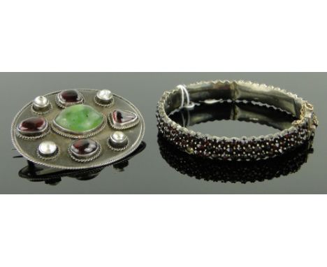 A Victorian garnet set hinged bangle,
together with a garnet, pearl and jade set brooch, unmarked settings, (2).