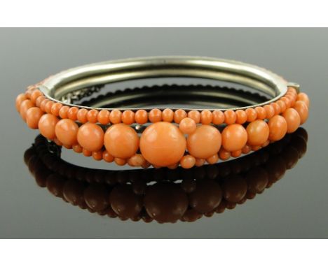 A Victorian coral mounted hinged bangle,
unmarked silver gilt settings.