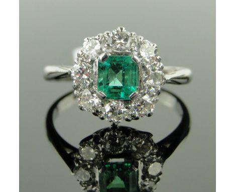 A platinum emerald and diamond cluster ring,
emerald approx. 0.62cts, total diamond content approx. 0.64cts, setting height 1