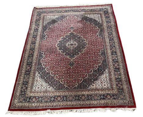 A large Persian red ground floral decorated carpet with geometric border, 400 x 295cm.