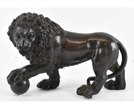 A bronze model of a lion with a ball in its left claw, length 22cm, height 15cm.Condition Report: Condition is good, no dents