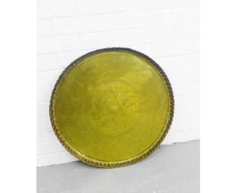 An Eastern brass circular tray top with crimpled edge and foliate and engraved calligraphy to the centre, diameter 62cm